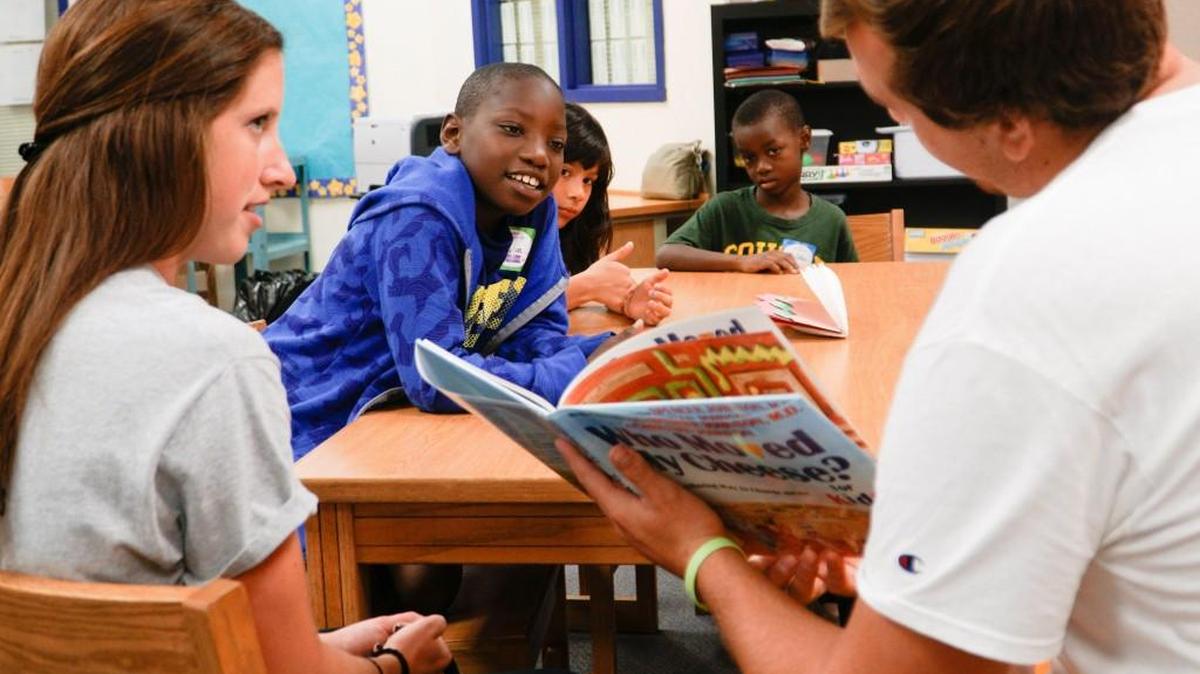 Adams Elementary student Jayden Kinnard listens to Wichita State University track athletes Abbi Bird and Jeff Ast read a book on Sept. 17, 2016.