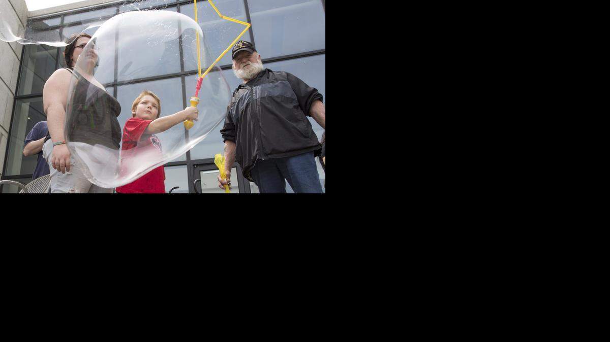 
Kaid Stevens creates giant bubbles at Exploration Place while his grandfather Mike Stevens, right, and mother, Kathryn Perry, watch. The three were at Exploration Place on Saturday, helping the facility celebrate its 15th birthday. (April 11, 2015)
