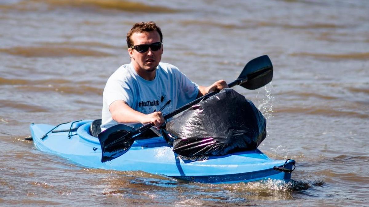 A volunteer on a kayak paddles back to shore with a trash bag during the 15th annual Arkansas River Trash Roundup in downtown Wichita on Saturday. (April 23, 2016)