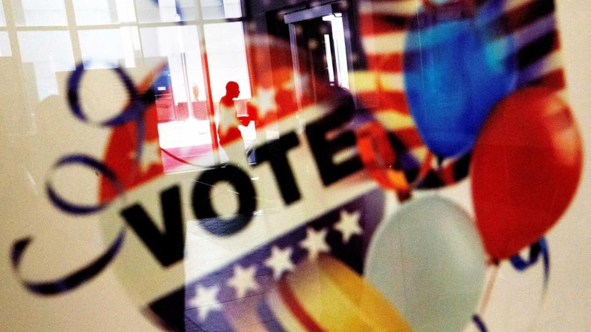 A voter is reflected in the glass frame of a poster while leaving a polling site in Atlanta, Ga., during early voting ahead of Election Day.