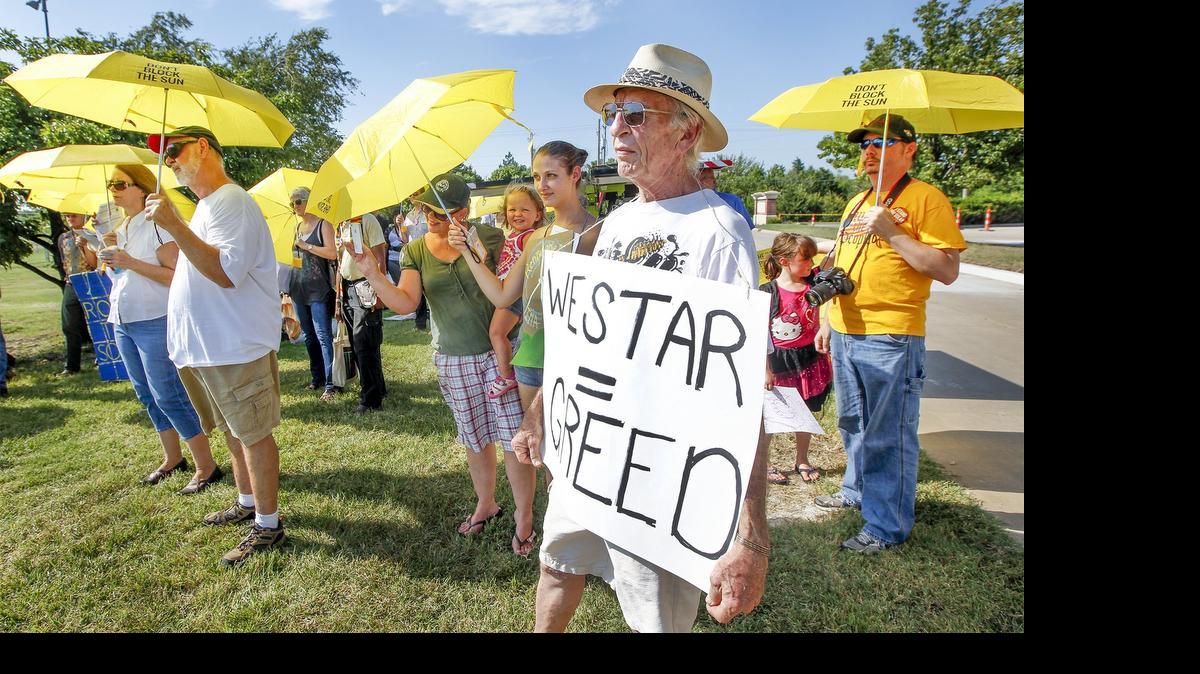 
Tommy Tuttle and other solar energy advocates, holding umbrellas that said “Don’t block the Sun,” gather before a public meeting involving a proposed rate increase by Westar Energy at the Hughes Metropolitan Complex on Thursday. (July 23, 2015)
