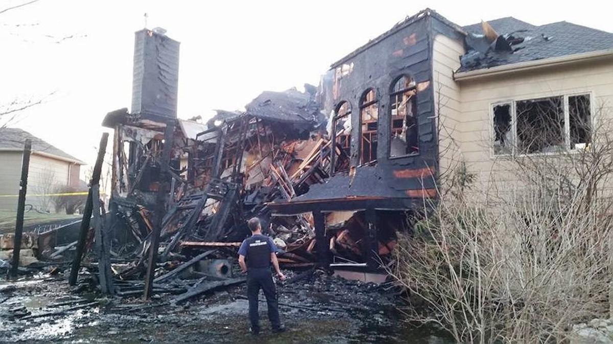 A fire investigator looks at damage to a house in west Wichita in late February. The fire was blamed on a discarded cigarette.