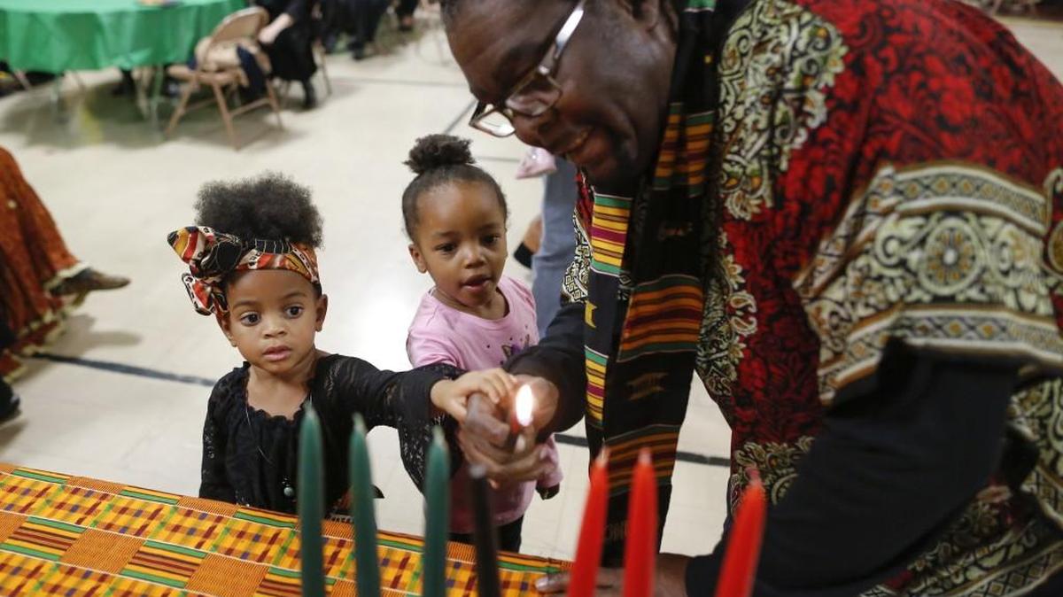 Kellyn Lattimore, left, and Raquel Lewis light a unity candle with the help of Terrill Florence during a Kwanzaa ceremony at the Urban Preparatory Academy on Monday. (Dec. 26, 2016)