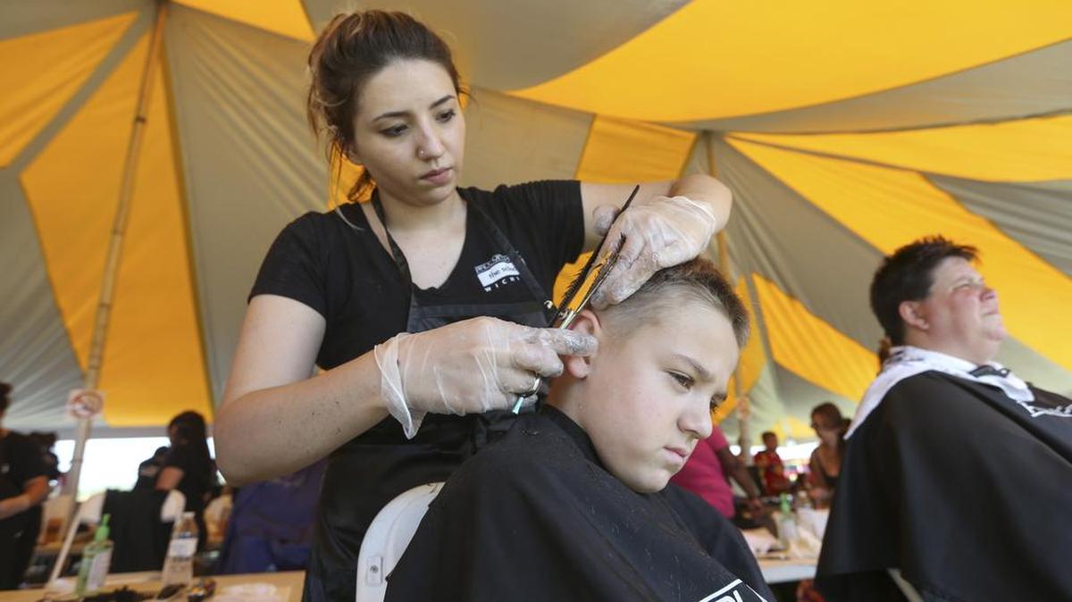 Volunteer Jazmin Frias gives 6-year-old Lucas Tasior a haircut during the Convoy of Hope event at the Bethel Life Center on Saturday. Convoy of Hope delivers free food, goods and services to residents in need.