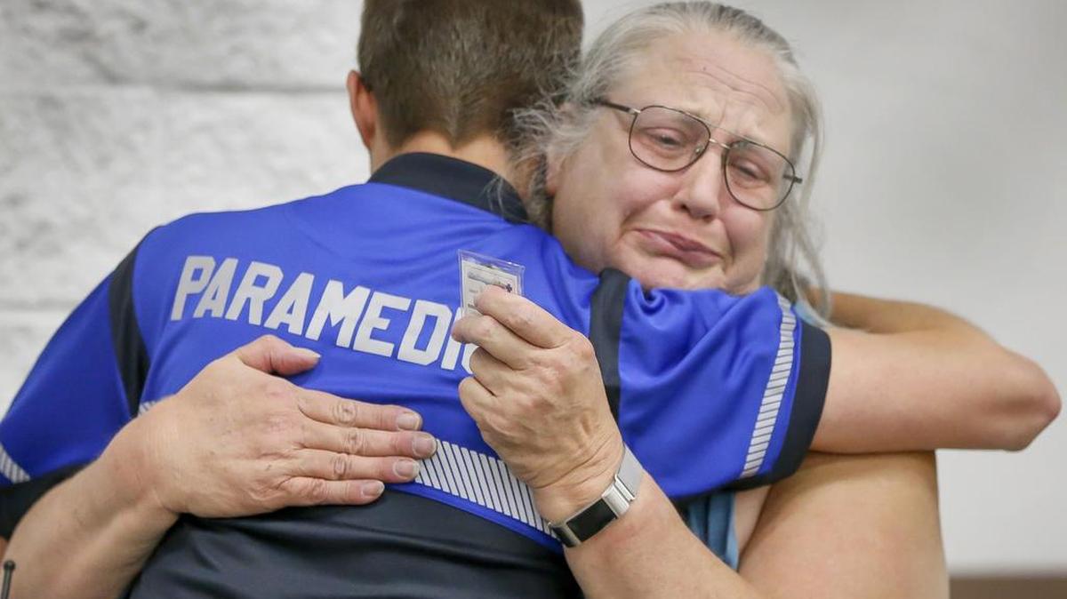 Kris Stehlik, right, hugs Sedgwick County paramedic Luke Ratzlaff, who saved her life when she suffered a heart attack at work, Wednesday during an EMS celebration at the Sedgwick County Extension Office. (May 24, 2017)
