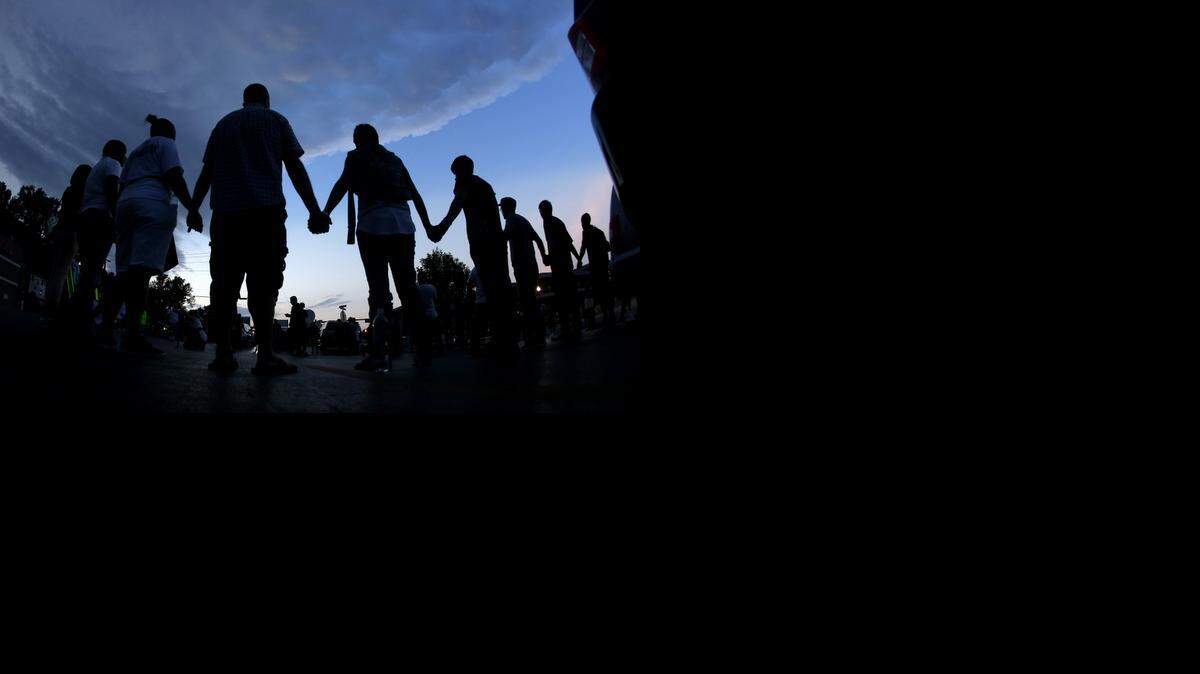 
People stand in prayer Aug. 20 in Ferguson, Mo., after marching about a mile to the police station to protest the shooting of Michael Brown on Aug. 9. A Wichita public meeting on Thursday, Aug. 28, to discuss how to better the relationship between local law enforcement and the public, will begin at 6:30 p.m. at East High School, 2301 E. Douglas. The forum will feature a panel discussion of community leaders including Wichita Mayor Carl Brewer, Wichita Interim Police Chief Nelson Mosley and Wichita Branch NAACP president Kenya Cox.
