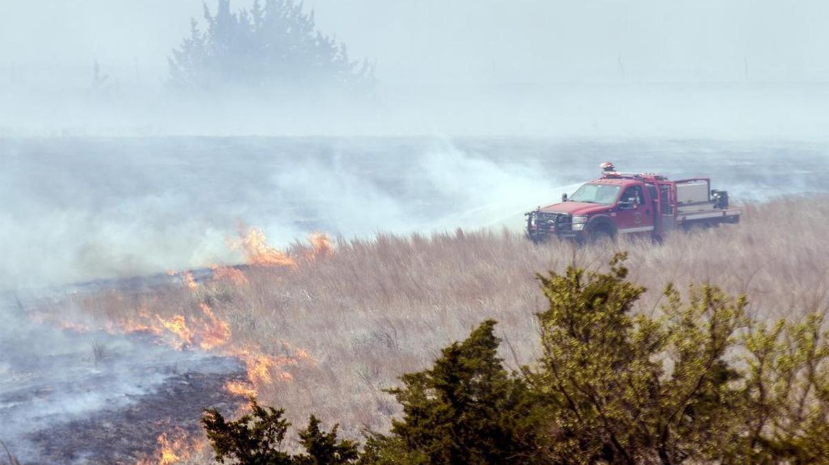 A firefighter crew douses a line of grass fire about 15 miles southwest of Medicine Lodge. More than 200 firefighters are battling an active fire line stretching 30 to 40 miles long in Barber County on Thursday morning. (Mar. 24, 2016)
