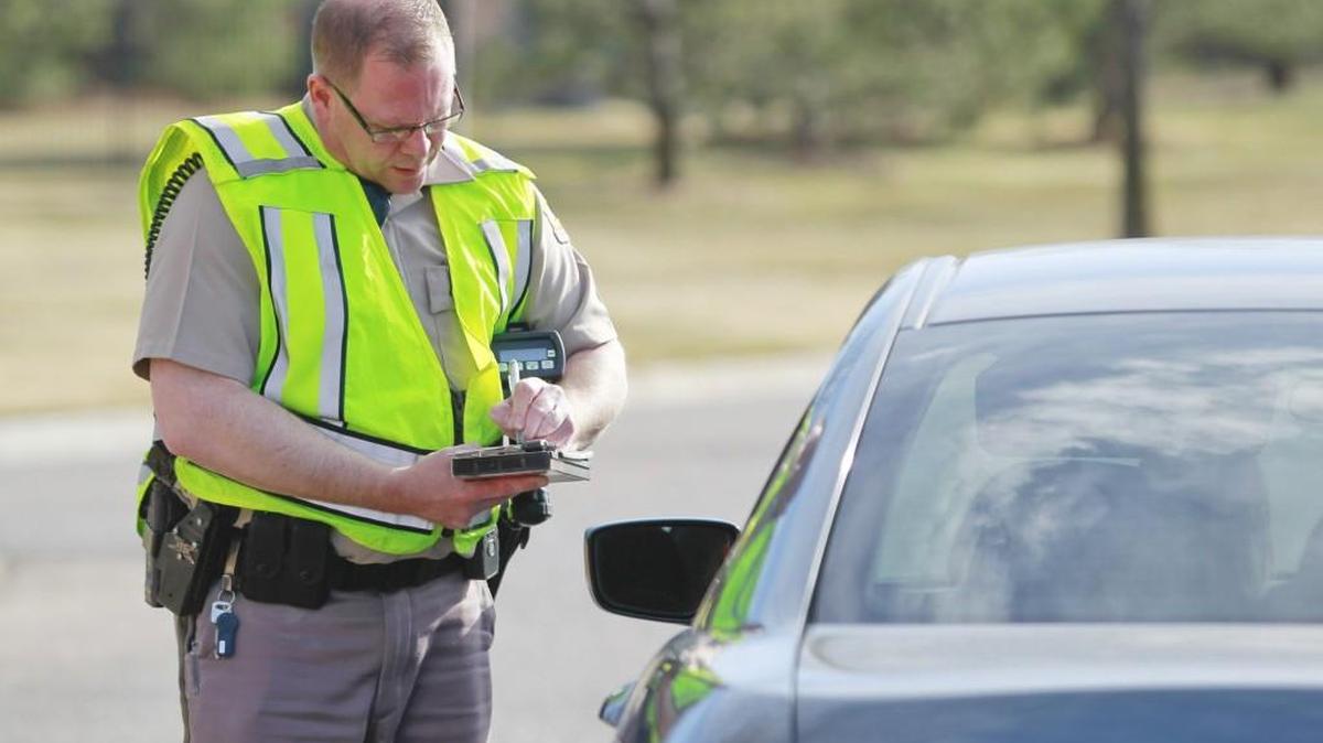 In this file photo, Wichita police officer Brian Safris writes a ticket to a motorist. The cost of a seat belt ticket is going up in Wichita. (June 9, 2014).