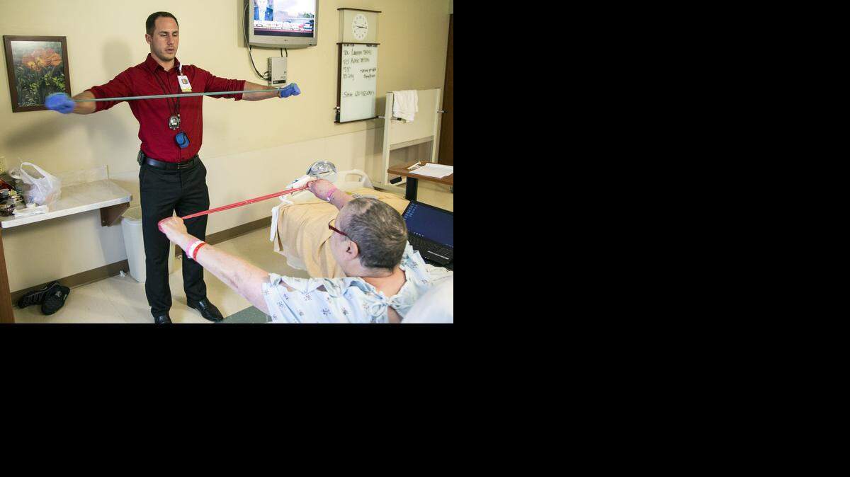 
Daniel Fowler is the coordinator of Via Christi’s Cancer Wellness Program, which aims to keep patients active during treatment and recovery. He uses resistance bands for strength with patients such as Beckie Helm. (Aug. 28, 2014.)
