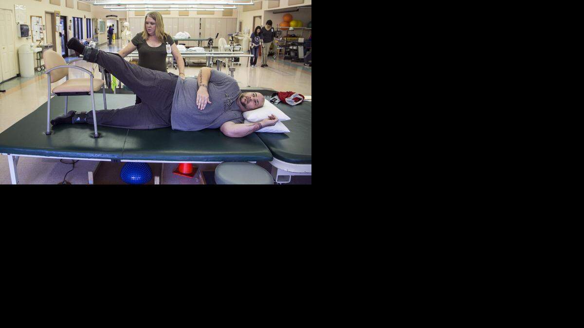 
Physical therapist Waneta Yoder works with Jason Schneiter, who has had congenital stenosis of the spine for year. He underwent surgery to relieve his pain but then became paralyzed. He now is able to walk again after physical therapy and another surgery. (Nov. 24, 2014) 
