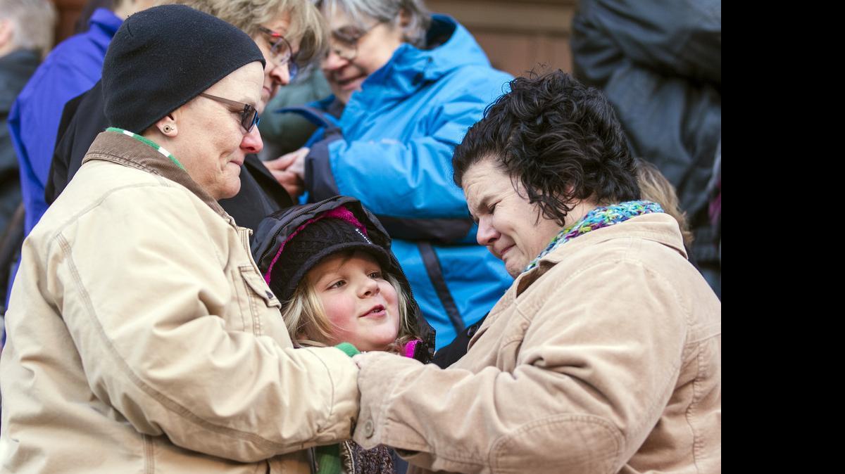 
Krista Casmaer, left, and Mindy Kufahl trade wedding bands, with Kufahl's daughter Phoebe Edgerton-Kufahl, 7, as a witness, during a mass same-sex marriage ceremony on the steps of the Historic Sedgwick County Courthouse in Wichita on Nov. 17, 2014. Kansas has had a constitutional ban against gay marriage since 2005, but some counties, including Sedgwick, began issuing marriage licenses to same-sex couples last fall after another court ruling. 
