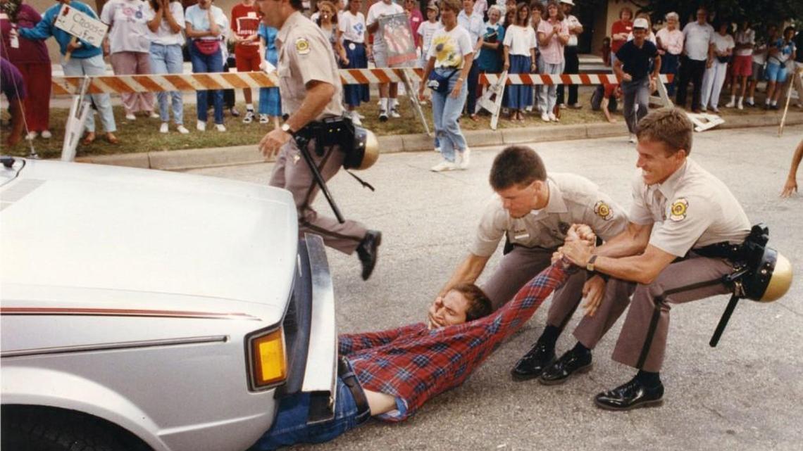 Wichita police officers attempt to remove an abortion protester from under a car at the entrance to physician George Tiller’s clinic during the “Summer of Mercy” protest in 1991.