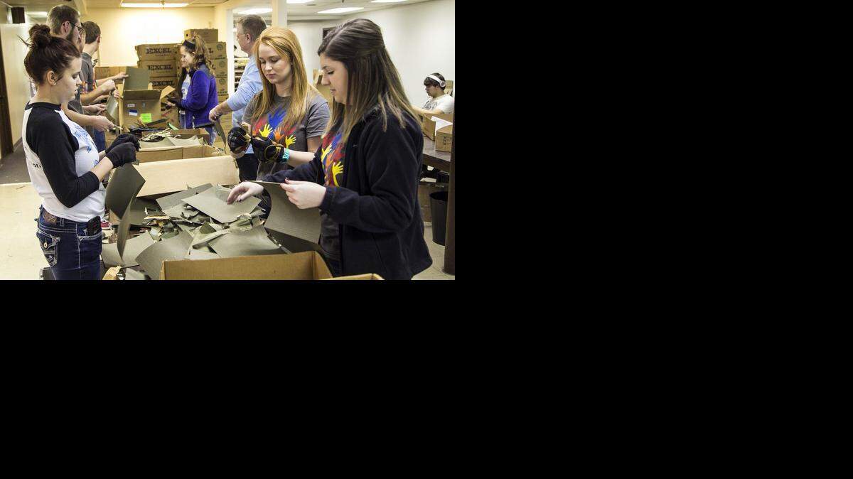 
Eisenhower High School students Casey Page, left, Riley Dohmeier and Sarah Kausse tear metal strips from paper notebooks for recycling at the United Way Give Items of Value warehouse. (Jan. 19, 2015)
