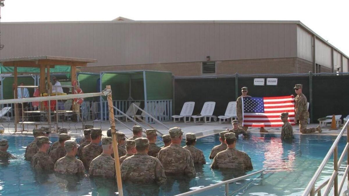 Soldiers in the Wichita-based 451st Expeditionary Sustainment Command hit the pool, in full uniform, to attend a re-enlistment ceremony for Sgt. Charles Smalley in Kuwait on Sunday.