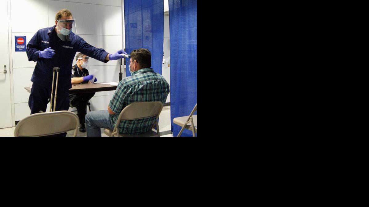 
U.S. Coast Guard Health Technician Nathan Wallenmeyer, left, and CBP supervisor Sam Ko conduct prescreening measures on a passenger, right, who arrived from Sierra Leone at O'Hare International Airport's Terminal 5 in Chicago. 
