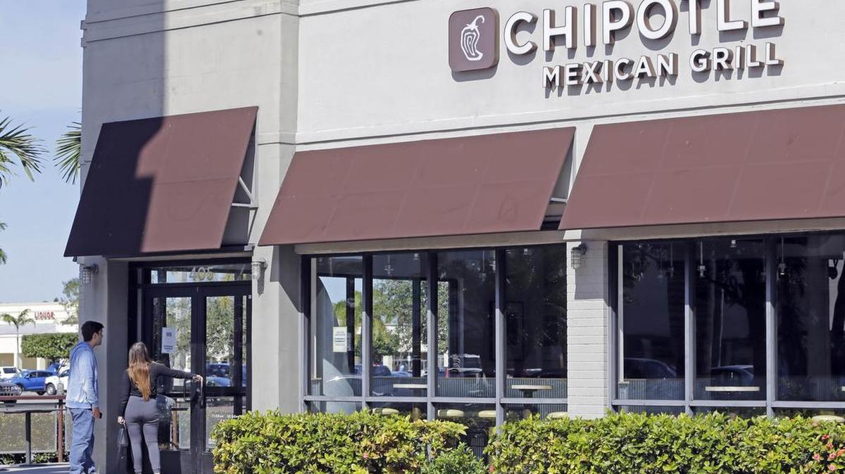A couple stand outside as they look at a sign of a closed Chipotle restaurant on Feb. 8 in Hialeah, Fla. An E. coli outbreak was traced to Chipotle restaurants in October. In December, the company also was tied to a norovirus incident in Boston, following outbreaks of the pathogen earlier in the year at outlets in California and Minnesota.