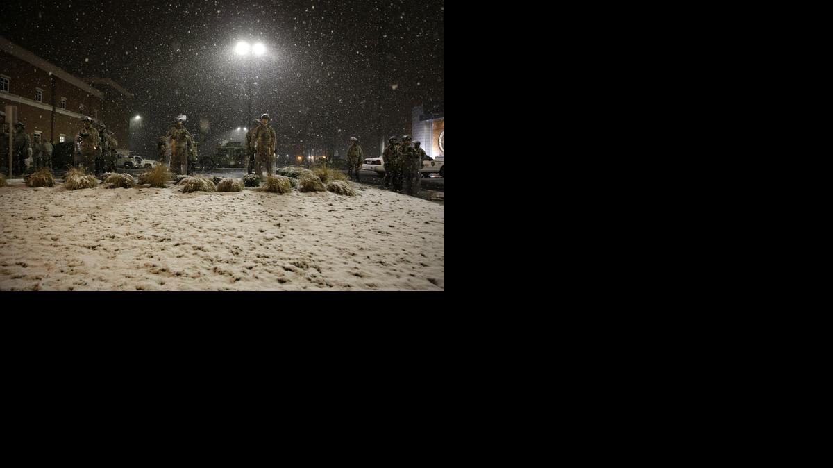 
Snow falls as Missouri National Guard troops stand guard outside of the Ferguson Police Department on Wednesday in Ferguson, Mo. 
