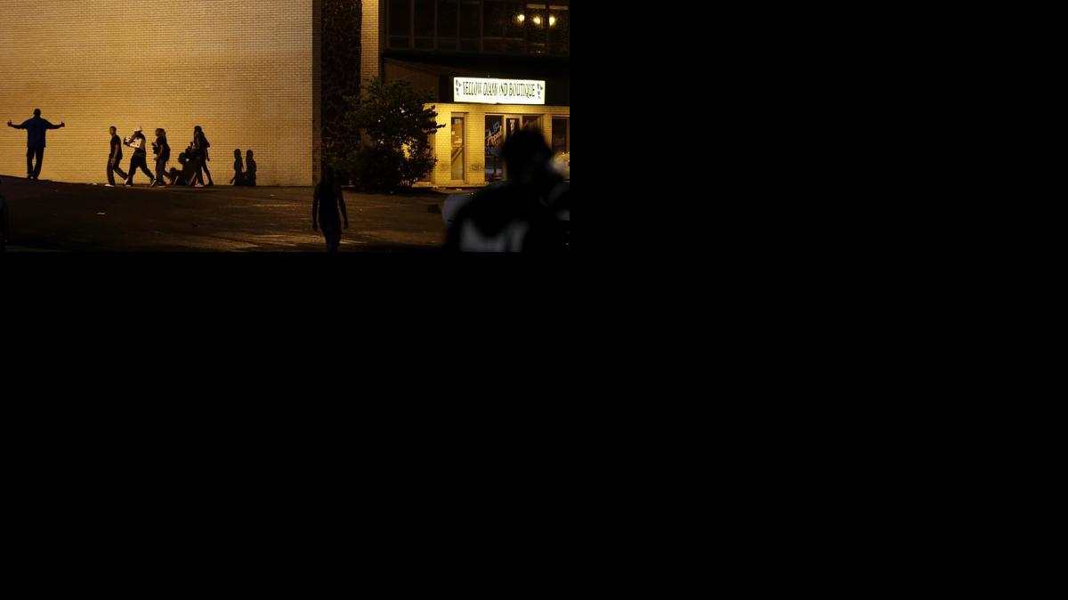 
People walk away from a shop after it was looted early Saturday, Aug. 16, 2014, in Ferguson, Mo. The violence stemmed from the shooting death of Michael Brown by police a week ago after the teen allegedly stole a box of cigars from the store. 
