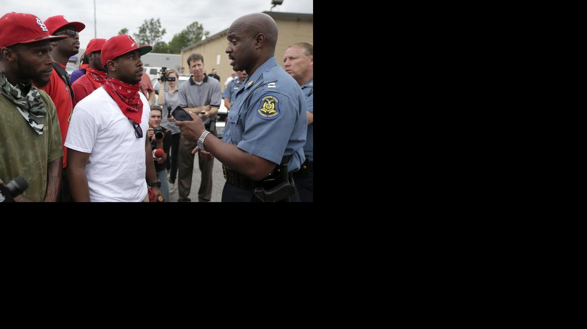 
Missouri Highway Patrol Capt. Ron Johnson, right, talks to a group of men outside a market, Friday, Aug. 15, 2014, where teenager Michael Brown allegedly stole some cigars before being killed by police nearly a week ago in Ferguson, Mo. Ferguson Police Chief Thomas Jackson identified the officer whose fatal shooting ignited days of heated protests, and released documents alleging the teen was killed after a robbery in which he was suspected of stealing a box of cigars.
