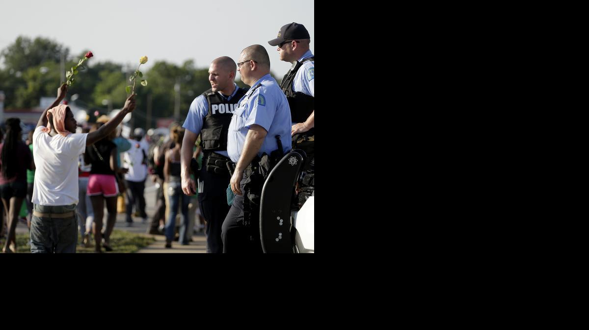 
Police watch as protesters march Tuesday for Michael Brown in Ferguson, Mo. Ferguson's leaders urged residents Tuesday to stay home after dark to "allow peace to settle in."
