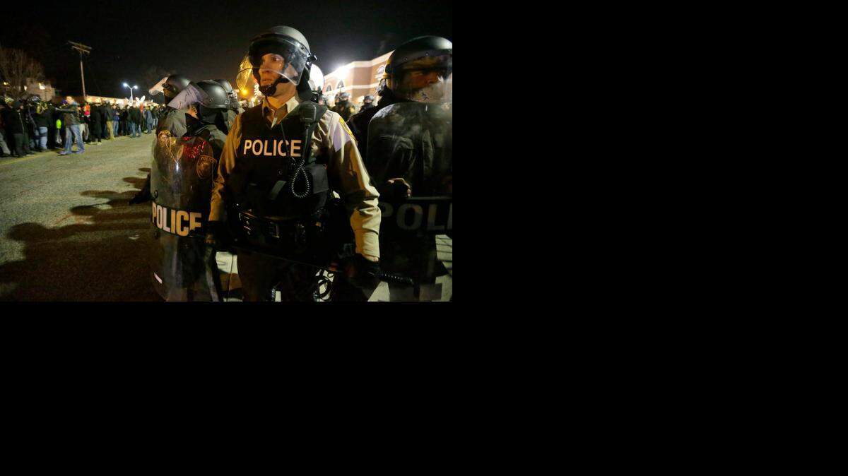 
Police watch the street last week as protesters gather in Ferguson, Mo. 
