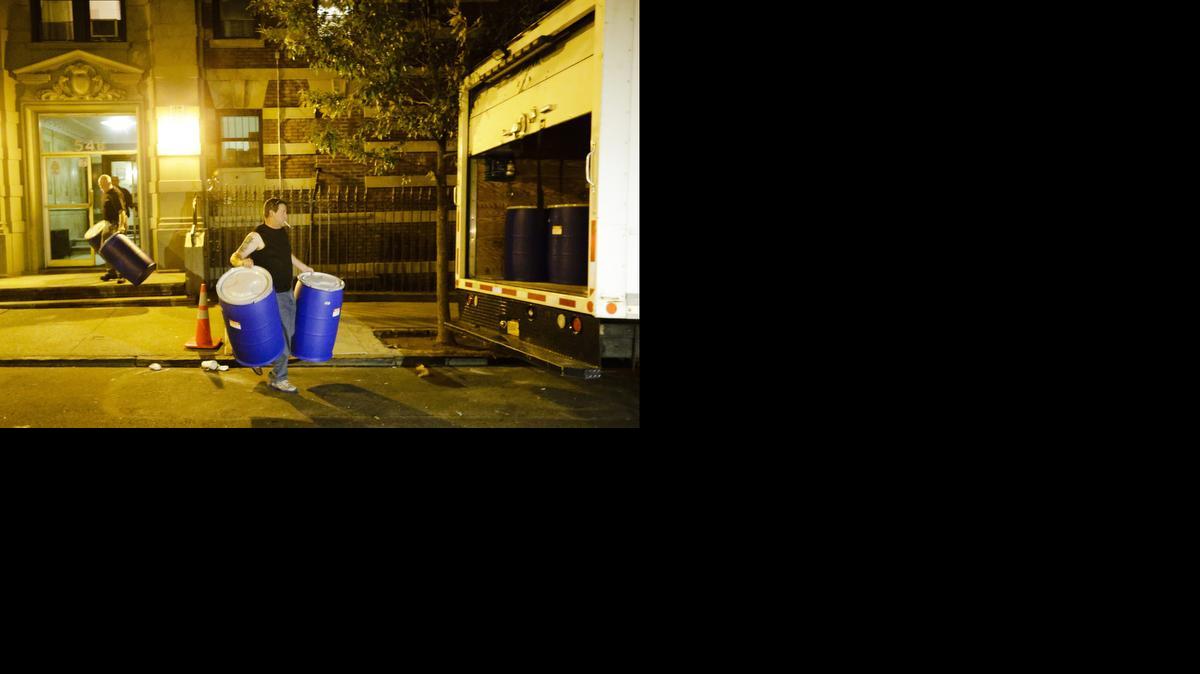 
Workers from BioRecoveryCorp carry barrels from the apartment building of Ebola patient Dr. Craig Spencer on Friday in New York. Spencer remained in stable condition while isolated in a hospital.
