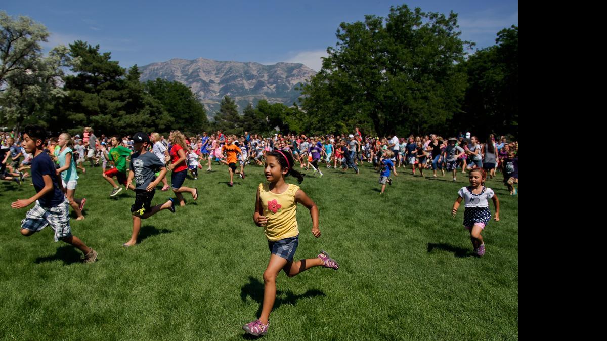 
Kids run to collect candy dropped by Gail Halvorsen, known as the "Candy Bomber," from a plane Friday at a park in Orem, Utah. 
