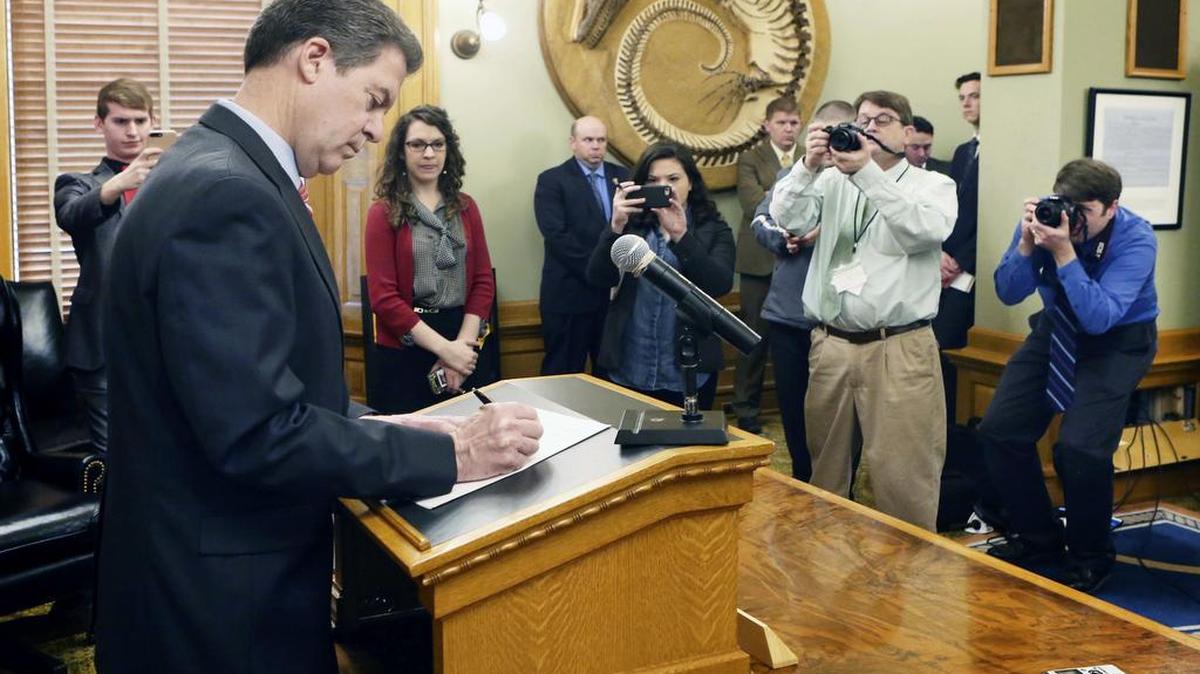 After announcing he would veto the tax bill sent to him by the Legislature, Gov. Sam Brownback officially signs the veto, in his ceremonial office on Feb. 22.