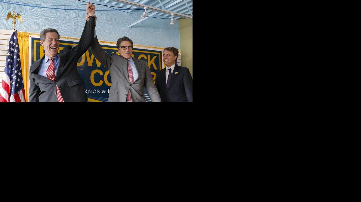 
Kansas Gov. Sam Brownback, left, has his arm raised in the air by Texas Gov. Rick Perry during a campaign rally for Brownback on Wednesday.
