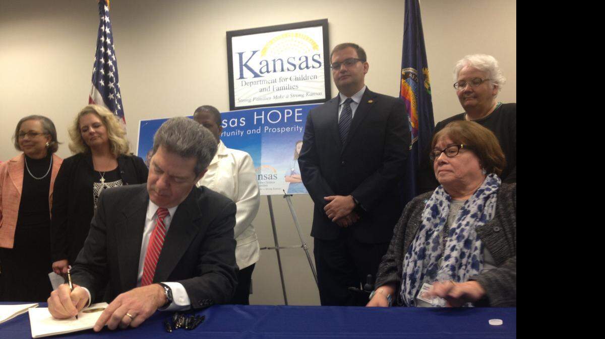 
Gov. Sam Brownback signs a bill tightening restrictions on use of welfare benefits. Phyllis Gilmore, secretary of the Department for Children and Families, sits at the governor’s left.
