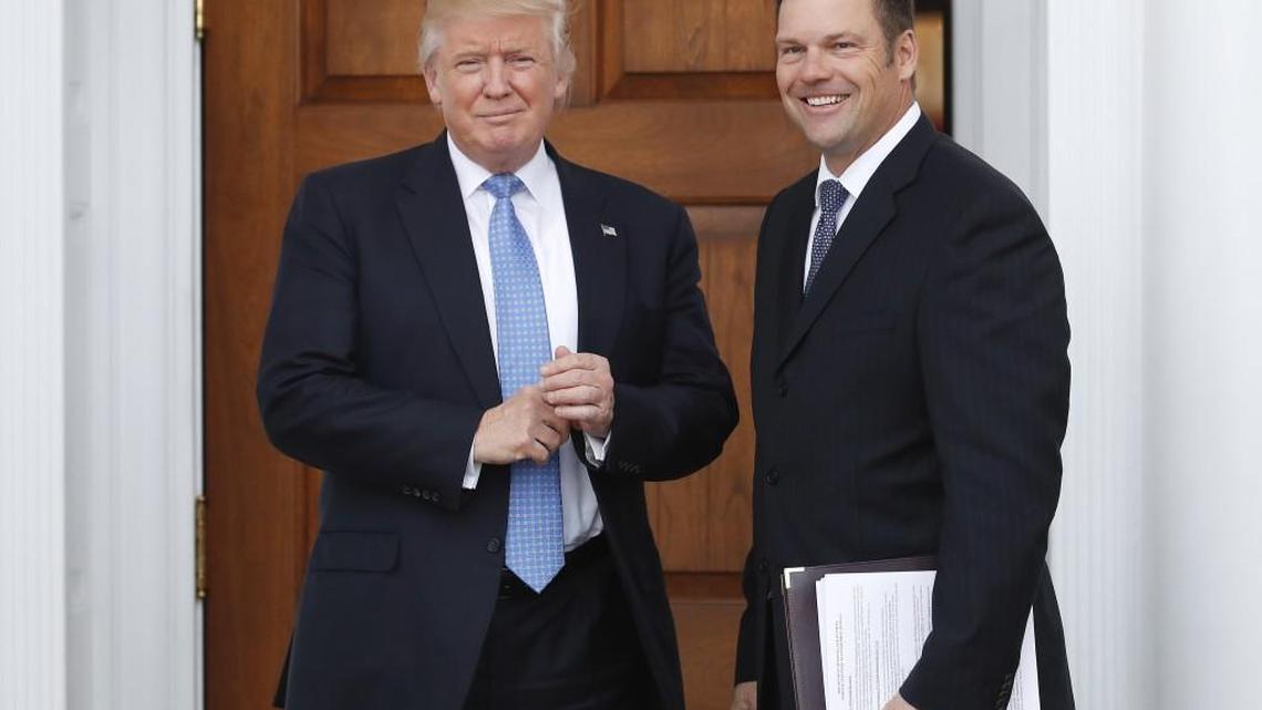 Kansas Secretary of State Kris Kobach, right, carries paperwork as he is greeted before a meeting with then-President-elect Donald Trump in November.