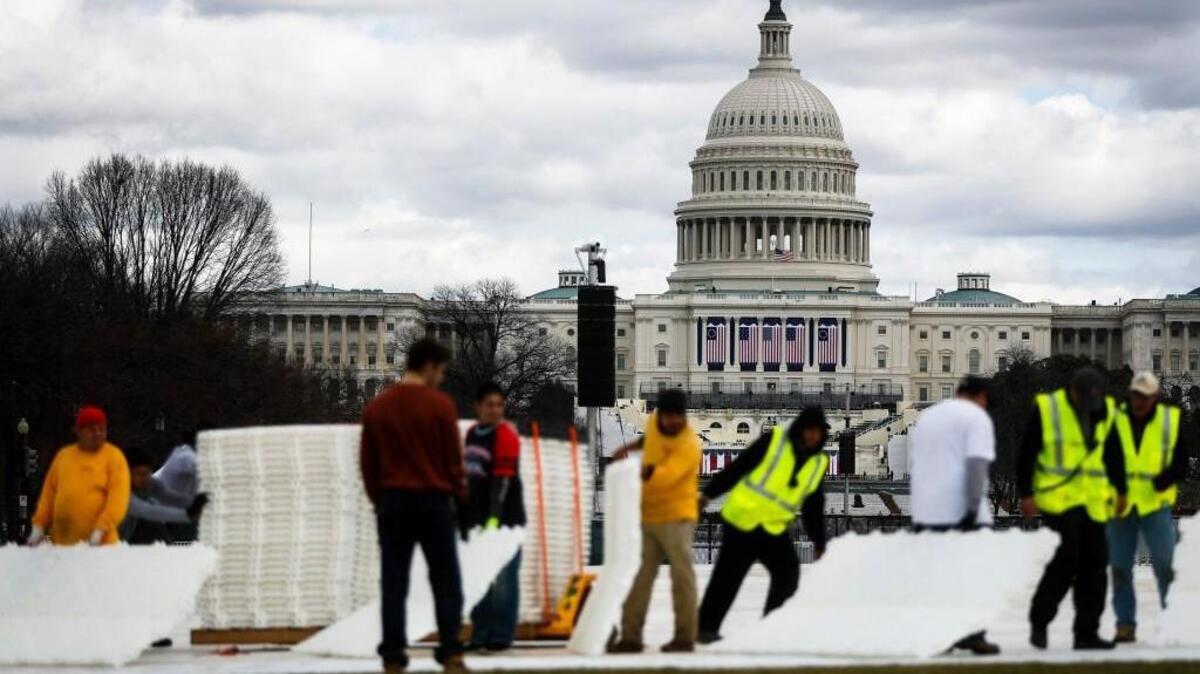 Workers place plastic flooring on the grass of the National Mall in Washington on Wednesday in preparation for Friday’s presidential inauguration. (Jan. 18, 2017)