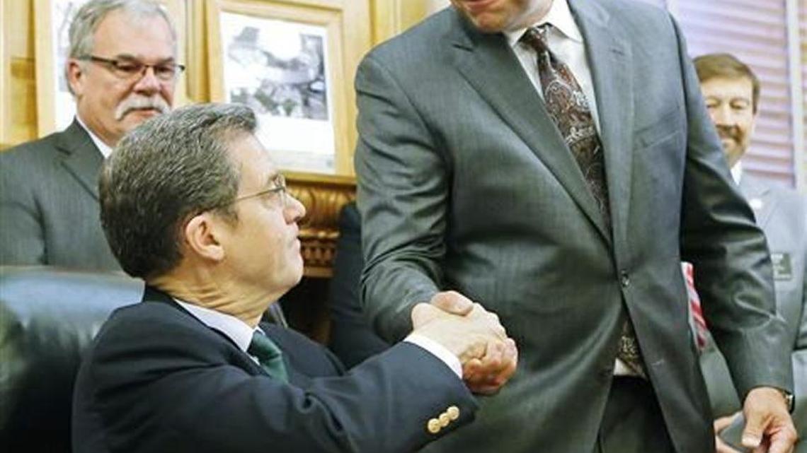 Kansas Secretary of State Kris Kobach, right, and Gov. Sam Brownback, seated, both plan to attend President-elect Trump’s inauguration on Friday.