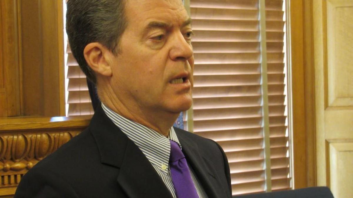 Gov. Sam Brownback talks to reporters Friday.