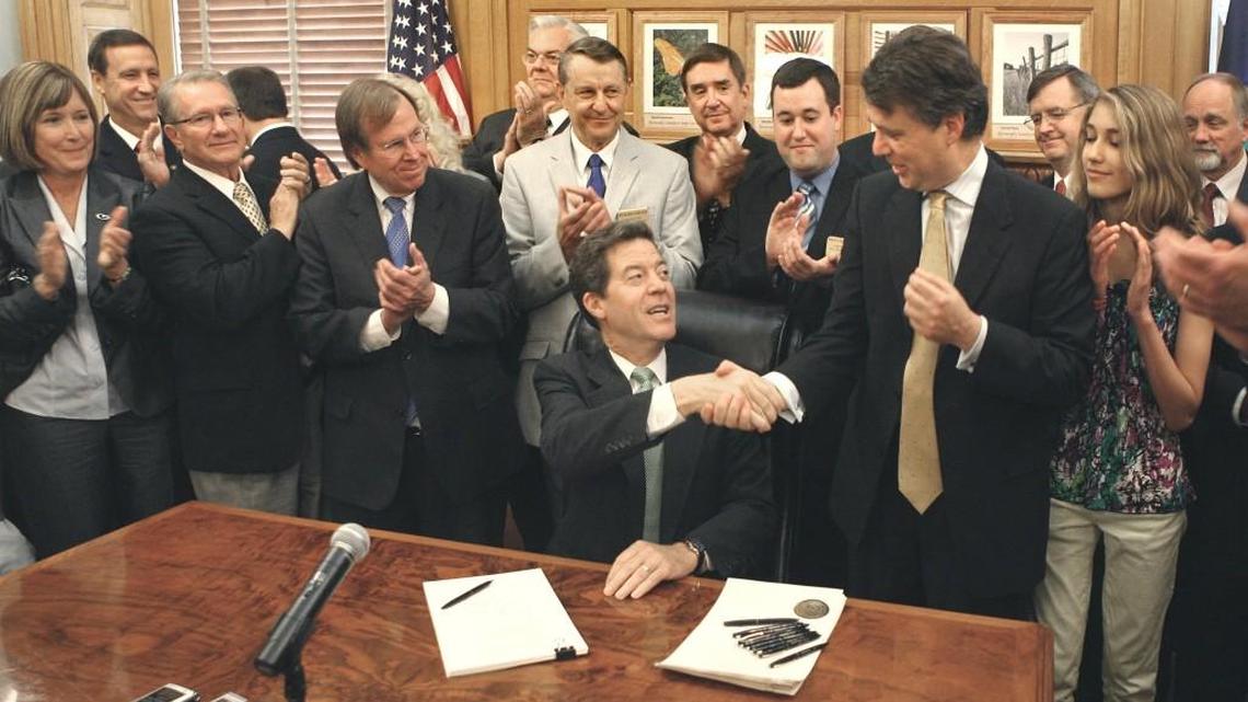 Gov. Sam Brownback shakes hands with Lt. Gov. Jeff Colyer in 2012 after signing into law one of the largest tax cut bills in Kansas history.