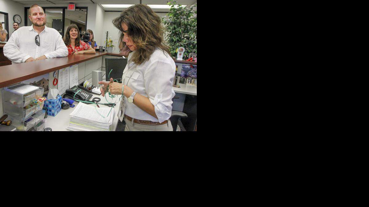 
Wichita City Clerk Karen Sublette unties the bundle of 5,800 petitions residents signed calling for the decriminalization of marijuana that was brought in by Esau Freeman, president and co-founder of Kansas for Change and Janice Bradley at City Hall. (July 24, 2014) 
