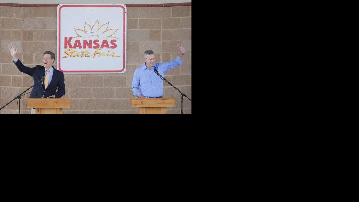 
Kansas Gov. Sam Brownback and his challenger Paul Davis wave to supporters after their debate on Saturday at the Kansas State Fair in Hutchinson. (Sept. 6, 2014)
