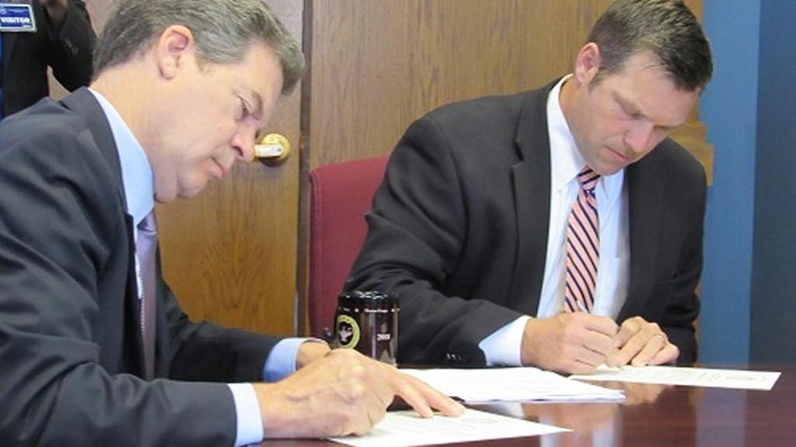 Gov. Sam Brownback and Secretary of State Kris Kobach sign and certify the results of the August primary on Thursday.