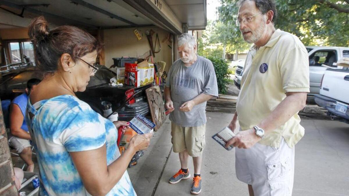 Sedgwick County Commissioner Karl Peterjohn, right, campaigns in a neighborhood near Maple and Ridge in June.