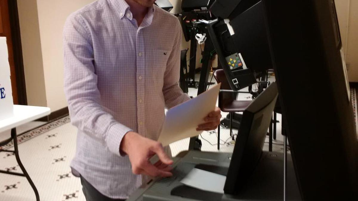 Dalton Glasscock, a campaign aide to congressional candidate Ron Estes, feeds his ballot into the new counting machine at the election commissioner’s office. (March 27, 2017)