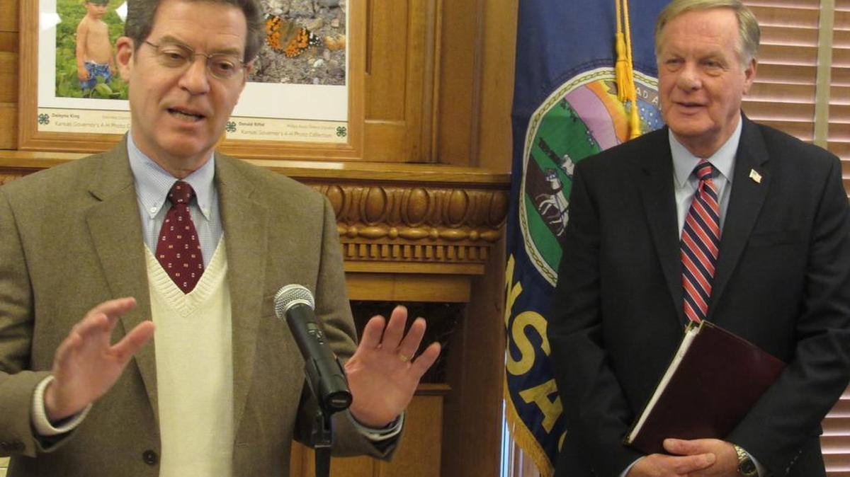 Kansas Revenue Secretary Nick Jordan, right, joins Gov. Sam Brownback at an event at the Capitol on Monday. Jordan refused to answer questions about revenue figures, which were set to be released the next day.