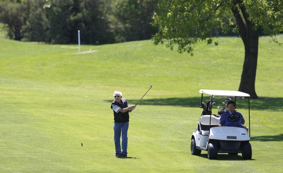 David Pankratz watches his ball after hitting from fairway on the 13th Hole at Tex Consolver public golf course. Golf partner Mike Bailey looks on from the cart. (May 18, 2015)