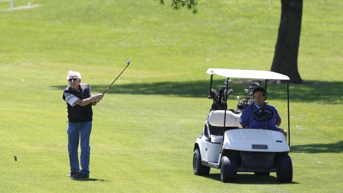 David Pankratz watches his ball after hitting from fairway on the 13th Hole at Tex Consolver public golf course. Golf partner Mike Bailey looks on from the cart. (May 18, 2015)