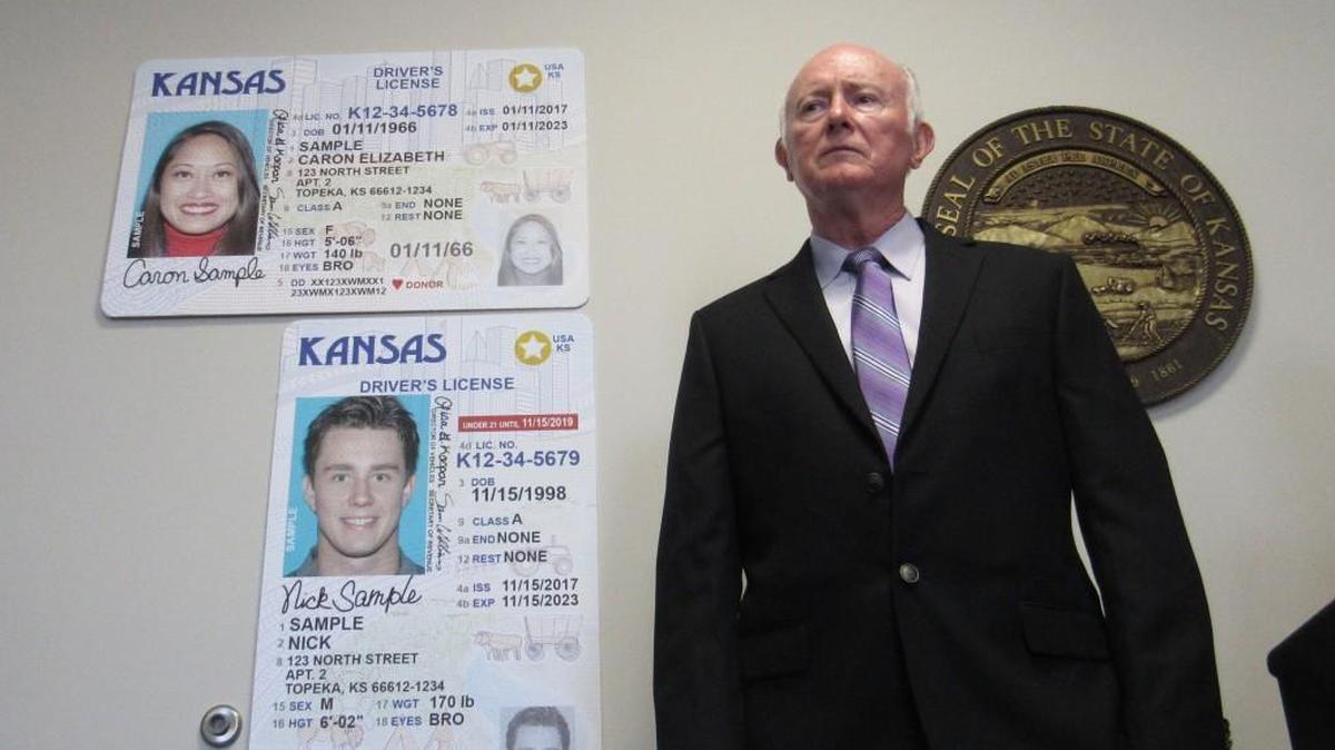 File photo of Revenue Secretary Sam Williams standing next to examples of new, Real ID-compliant Kansas driver licenses.