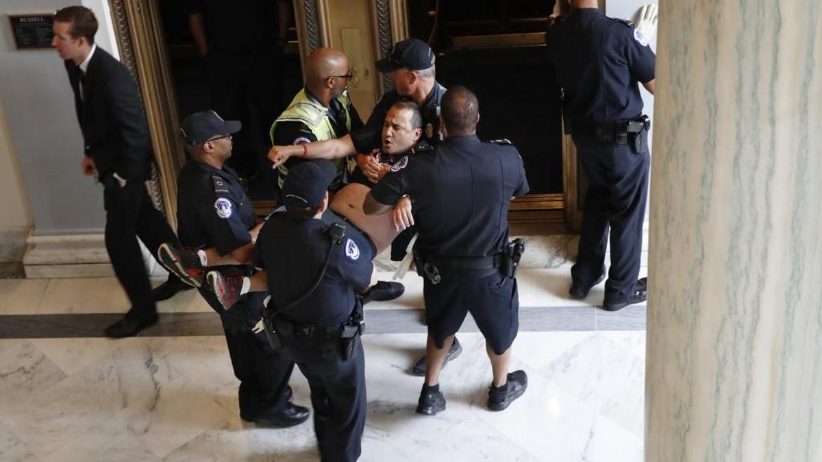 Capitol Police remove a man from a sit-in Thursday at Senate Majority Leader Mitch McConnell’s office. A group including those with disabilities was protesting proposed cuts to Medicaid.
