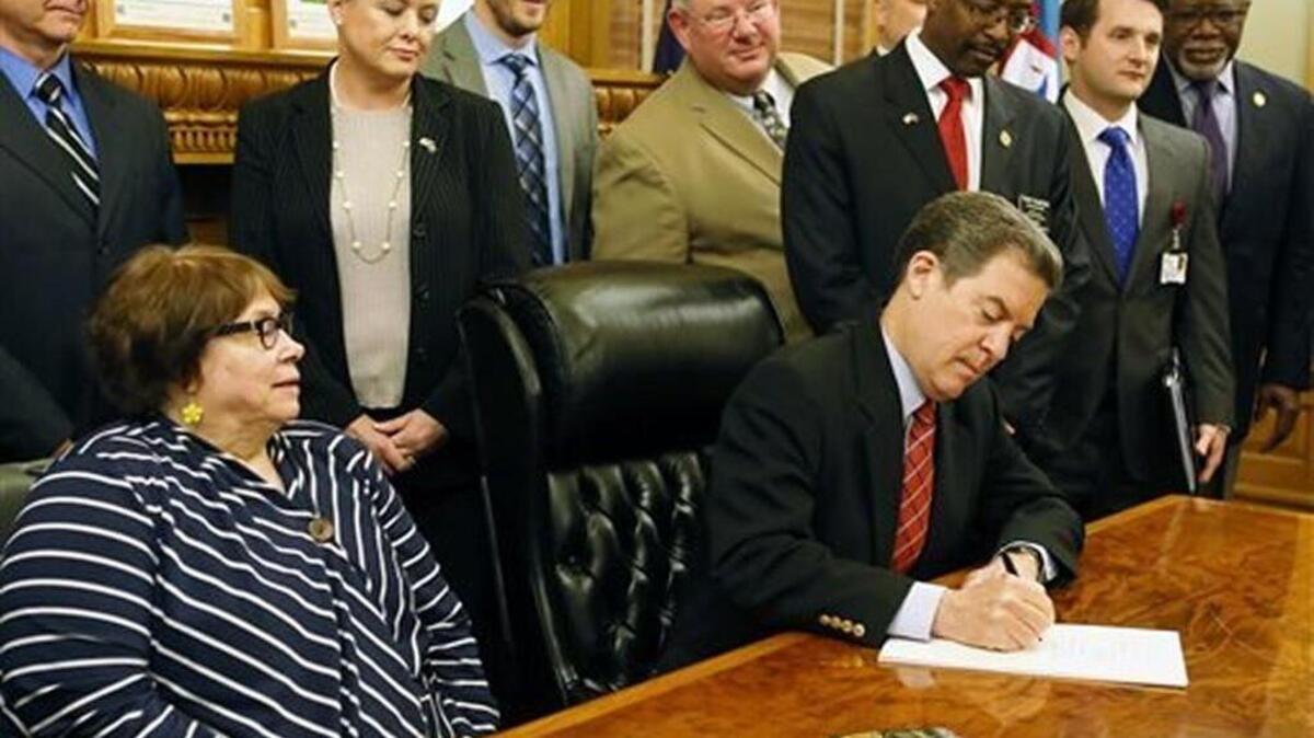 Gov. Sam Brownback, front right, signs legislation Monday, May 16, 2016, that will tighten the state's lifetime limits on cash assistance.