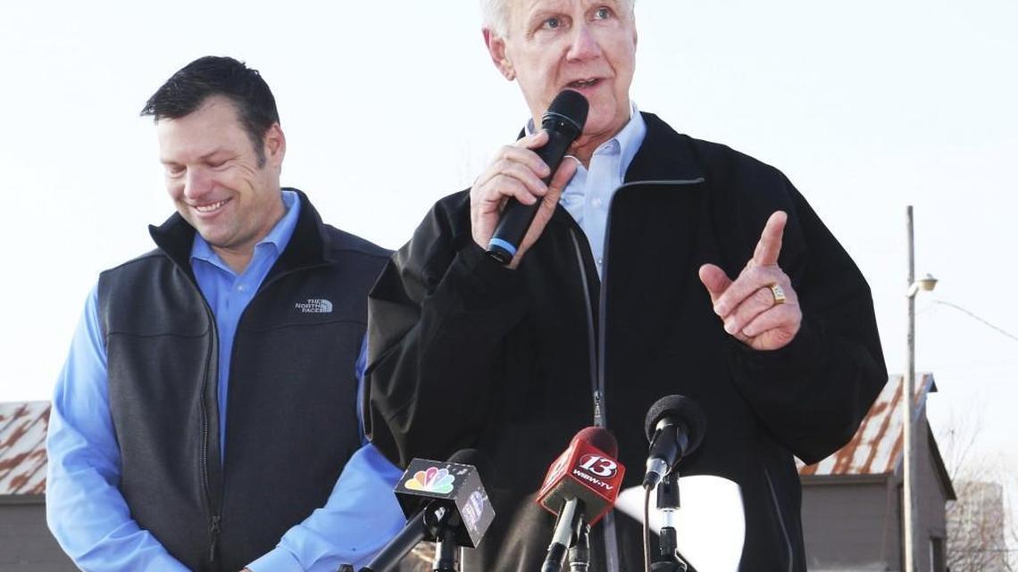 Kansas Secretary of State Kris Kobach, left, listens as Wink Hartman, right, speaks during a campaign stop Wednesday in Topeka.