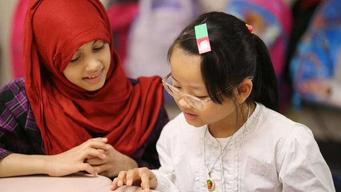 Fatimah Albusha, left, of Saudi Arabia and Anna Le of Vietnam work together to identify numbers in August at Washington Elementary School. Fatimah and Anna are in the school’s “newcomers” class for children from around the world, most of whom don’t speak English.