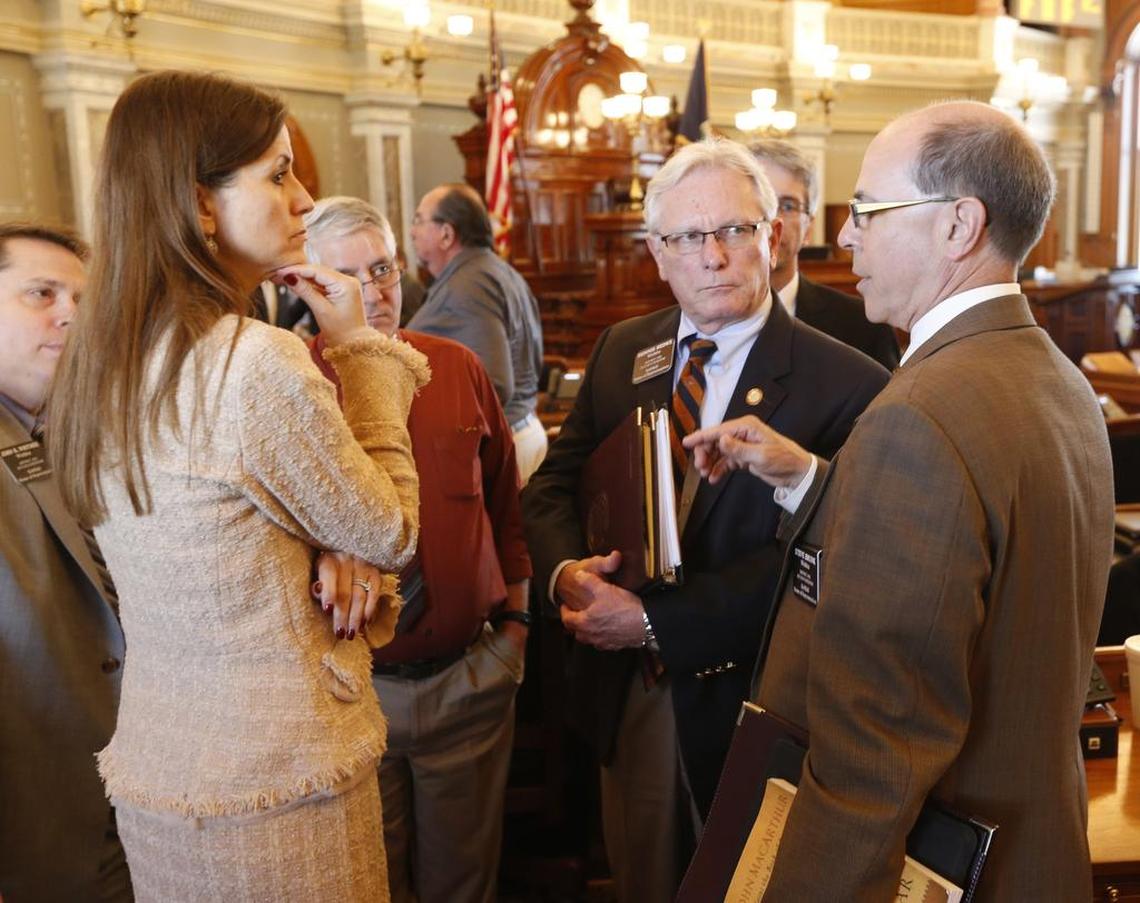 Wichita members of the Kansas House of Representatives including Rep. Kasha Kelley (left), Rep. Dennis Hedke (right center) and Rep. Steve Brunk (far right) gather after the House recessed Tuesday afternoon. 