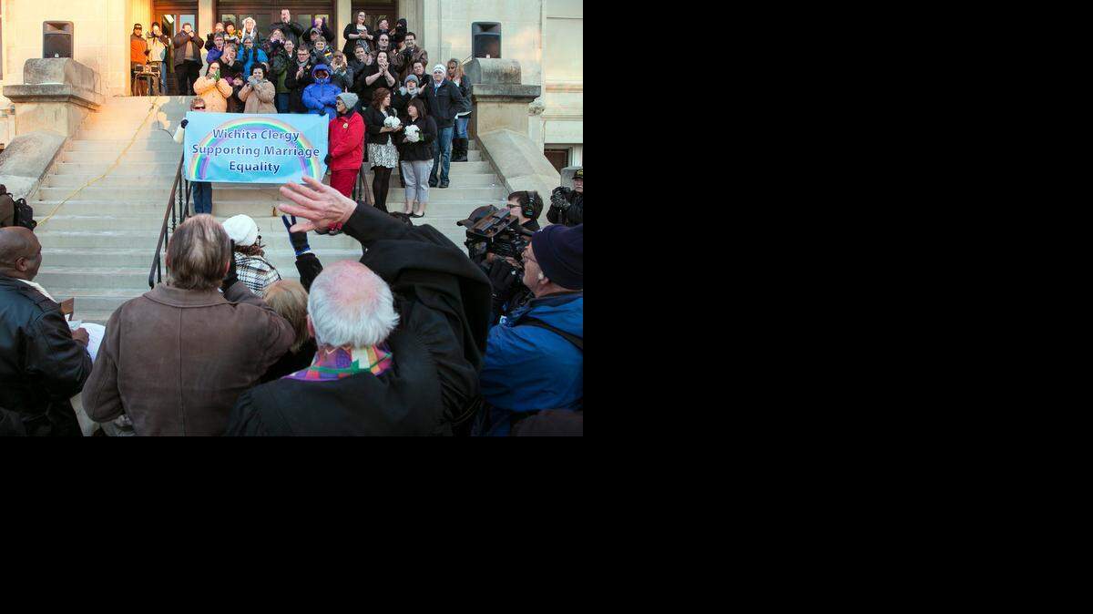 
A crowd cheers Monday as about 15 couples marry in a same-sex ceremony on the steps of the Historic County Courthouse in Wichita. (Nov.17, 2014)
